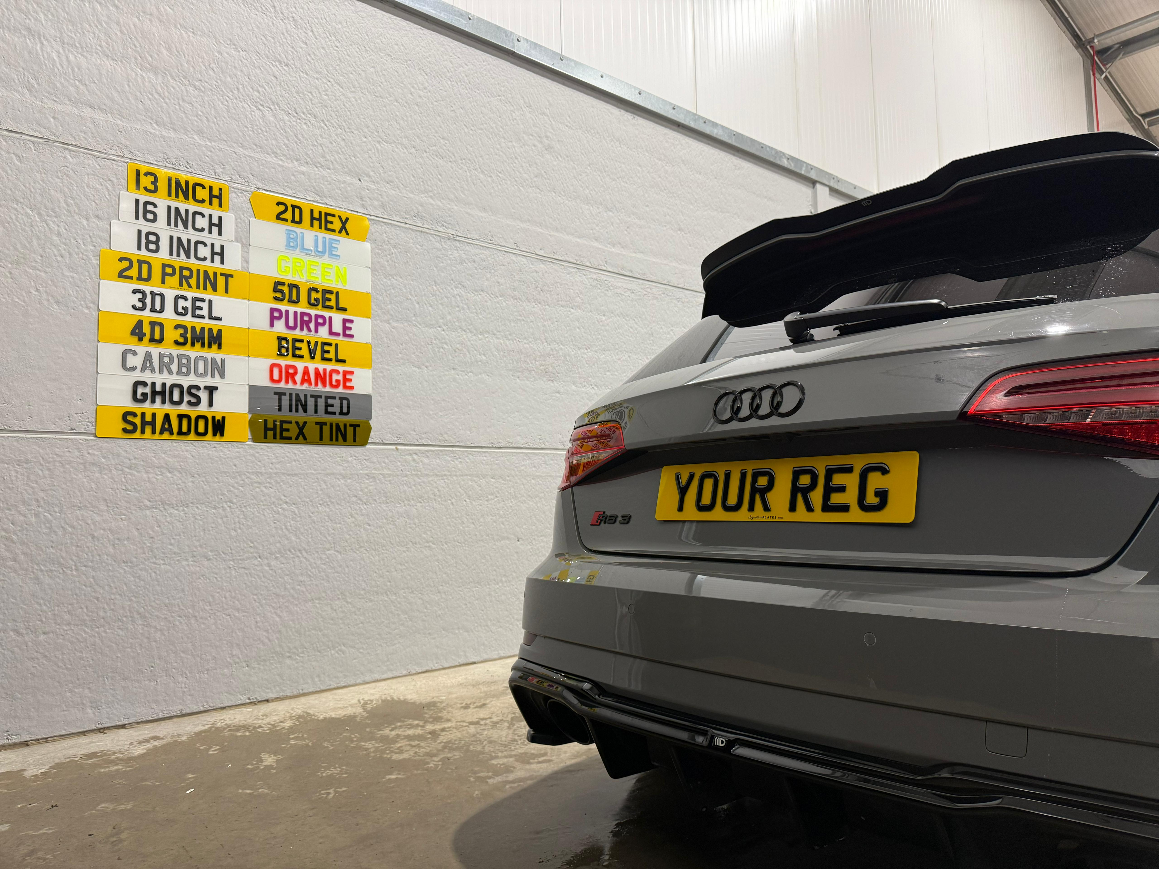 Audi with a custom license plate in front of a wall with multiple custom plates on.